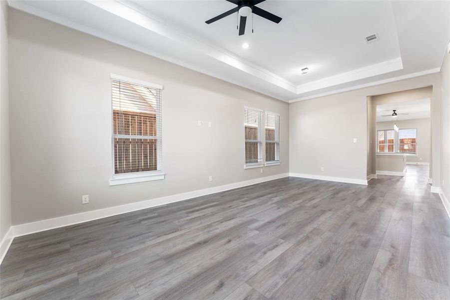 Empty room with a raised ceiling, ornamental molding, hardwood / wood-style floors, and ceiling fan