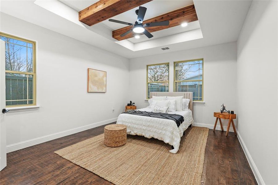 Bedroom with a tray ceiling, dark wood finished floors, and ceiling fan