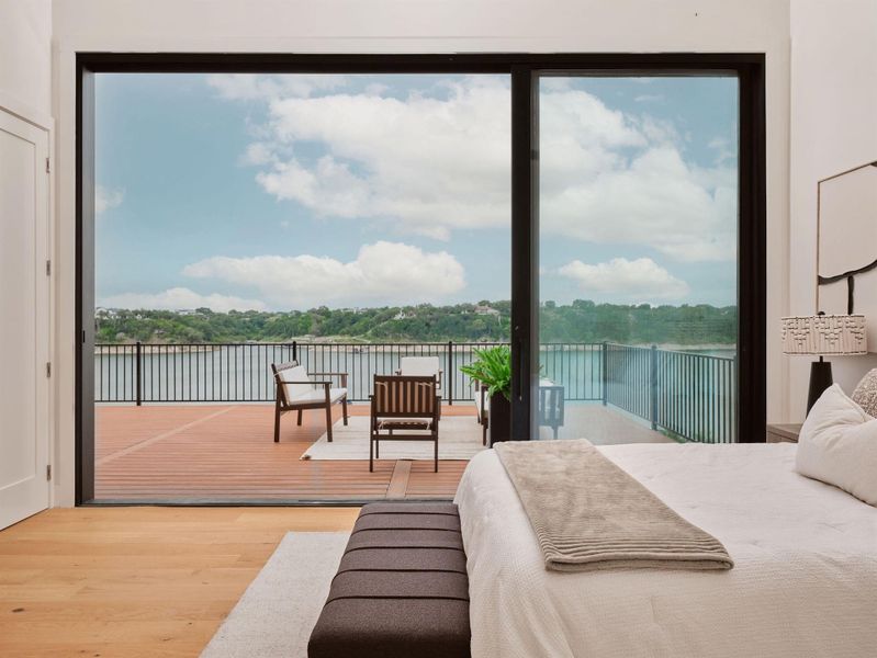 Expansive glass sliding doors open to a wide exterior deck featuring a black metal railing and water frontage