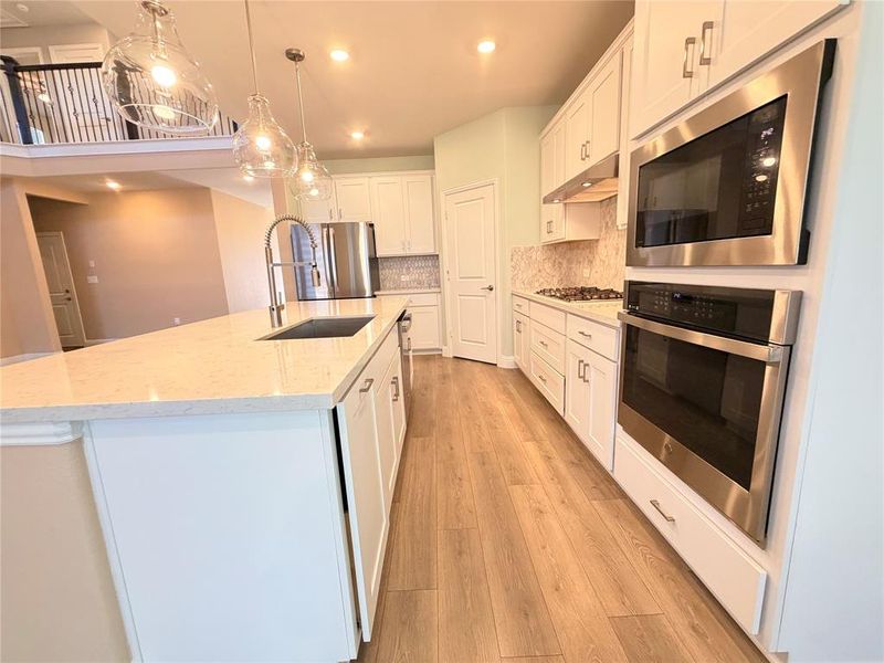 Kitchen with stainless steel appliances, white cabinets, decorative light fixtures, tasteful backsplash, and recessed lighting Kitchen with stainless steel appliances, white cabinets, decorative light fixtures, tasteful backsplash, and recessed lighting