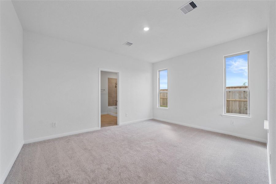 Relax and recharge in this stunning primary suite! Enjoy the comfort of plush carpeting, neutral toned walls, high ceilings, and windows that fill the room with natural light.