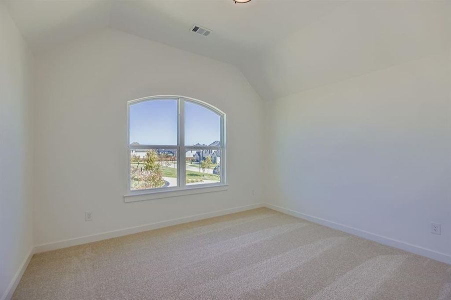 Spare room featuring light colored carpet and lofted ceiling Spare room featuring light colored carpet and lofted ceiling