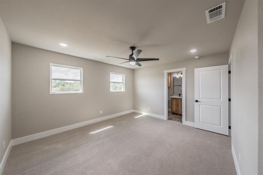 Unfurnished bedroom featuring carpet flooring, recessed lighting, ceiling fan, and ensuite bath Unfurnished bedroom featuring carpet flooring, recessed lighting, ceiling fan, and ensuite bath