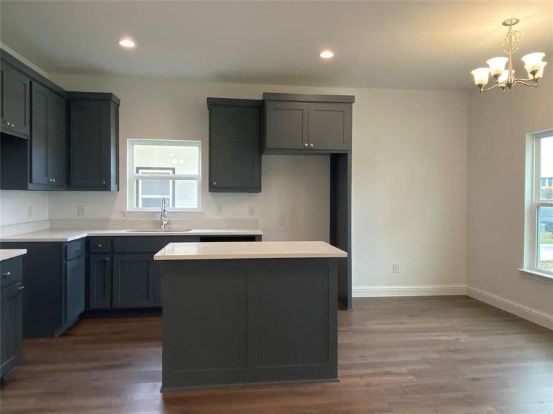 Kitchen featuring dark wood-type flooring, recessed lighting, a chandelier, a center island, and decorative light fixtures Kitchen featuring dark wood-type flooring, recessed lighting, a chandelier, a center island, and decorative light fixtures