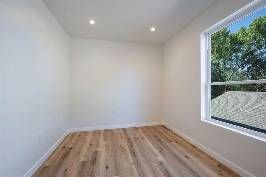 Bedroom featuring light hardwood / wood-style floors with custom oversized windows