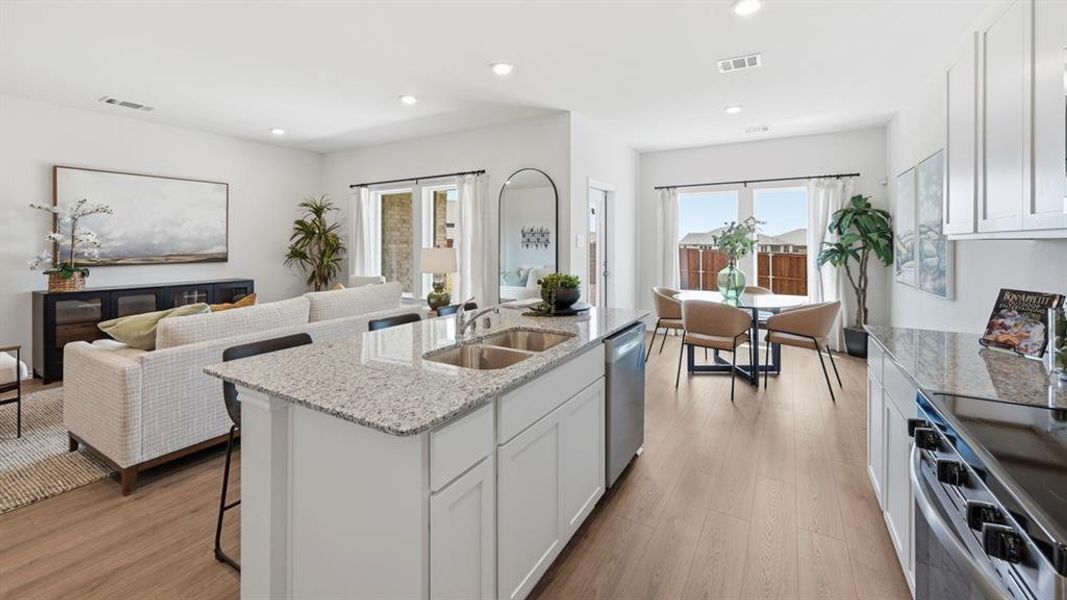 Kitchen with white cabinets, stainless steel appliances, light stone counters, light wood-type flooring, and recessed lighting