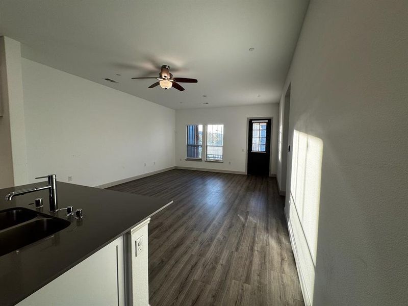 Unfurnished living room featuring dark hardwood / wood-style flooring, ceiling fan, and sink