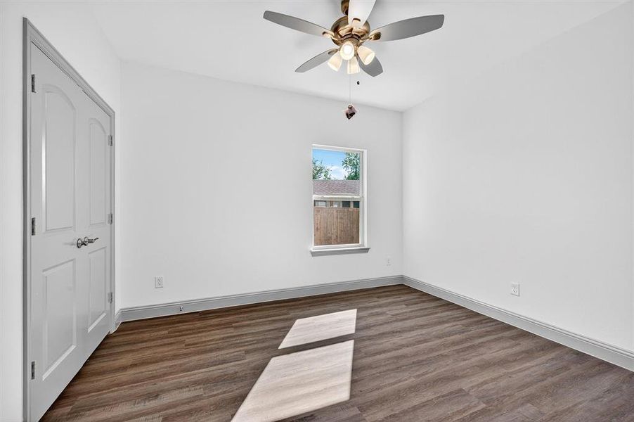 Unfurnished bedroom with dark wood-style floors and a ceiling fan