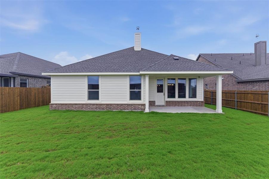 Expansive rear yard featuring a covered patio, brick and siding exterior, and a dark shingle roof