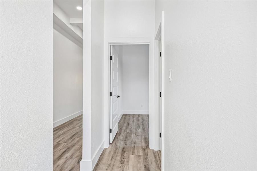 Interior hallway featuring light wood-finish flooring, white walls, and a recessed ceiling light