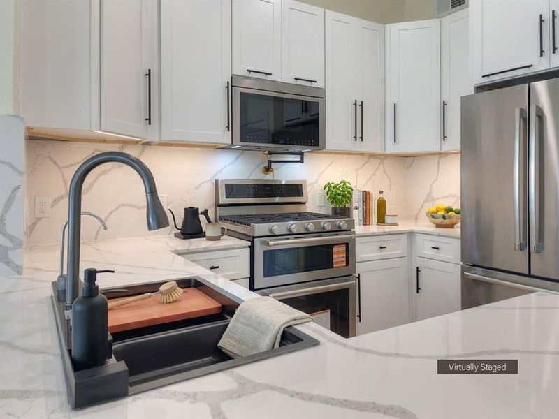 Contemporary kitchen featuring white cabinetry with matte black hardware, stainless steel appliances, and a gas range with a double oven