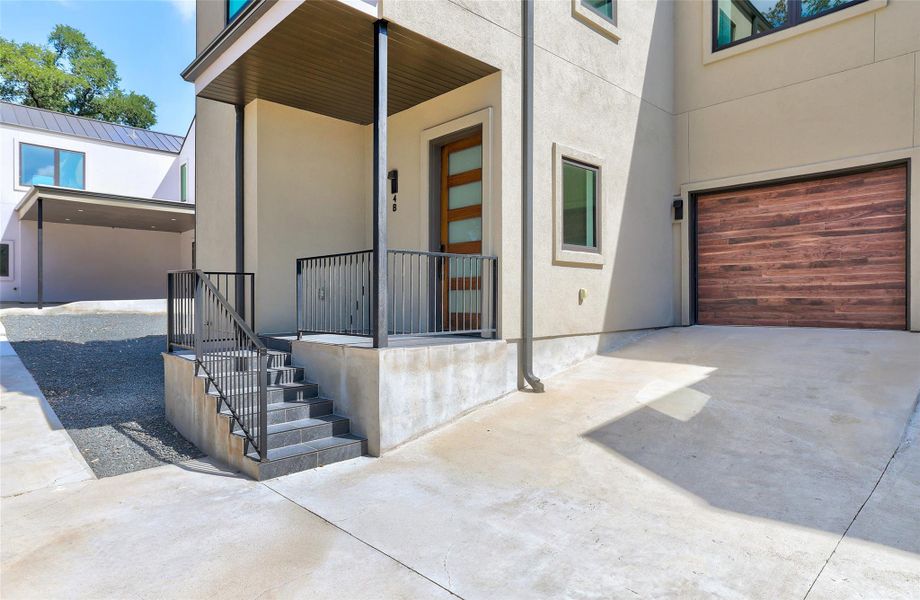 Entrance to property with stucco siding, concrete driveway, a metal roof, and a garage