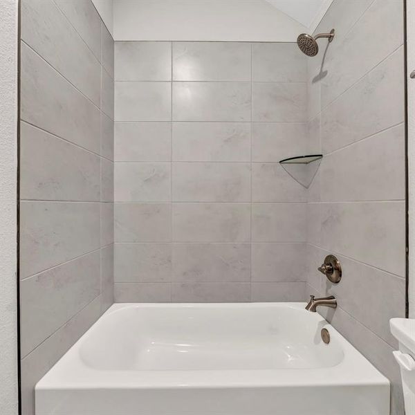 Bathroom featuring tiled shower / bath combo and toilet