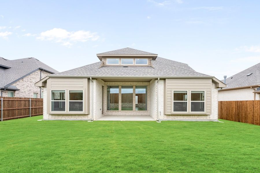 Rear exterior of single-story home with brick siding, hip roof, covered patio, and fenced backyard lawn Rear exterior of single-story home with brick siding, hip roof, covered patio, and fenced backyard lawn
