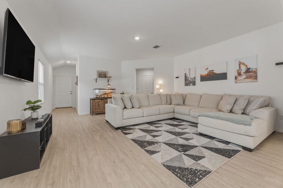 The open-concept living area features light-colored flooring, white walls, and recessed lighting