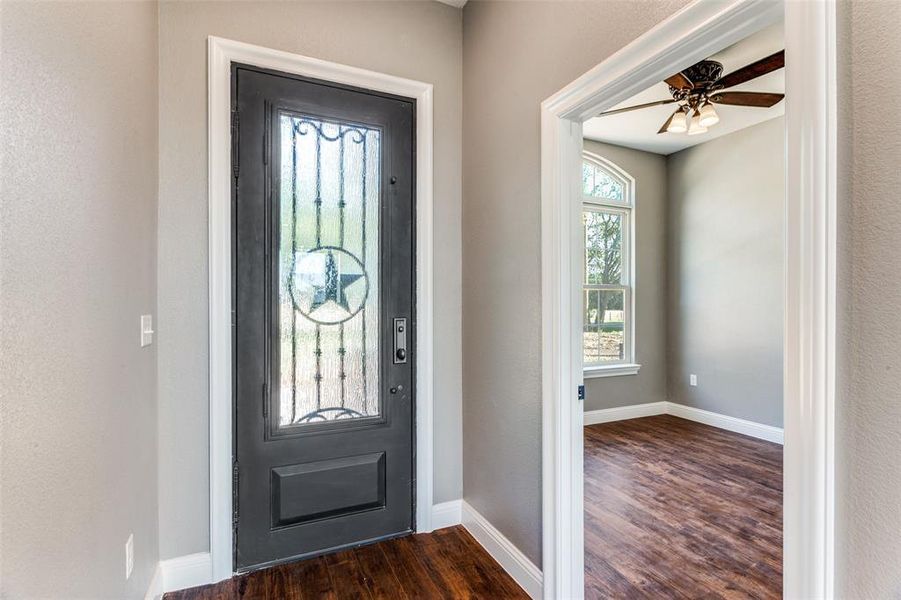 Foyer entrance with dark wood-type flooring, a textured wall, and a ceiling fan Foyer entrance with dark wood-type flooring, a textured wall, and a ceiling fan