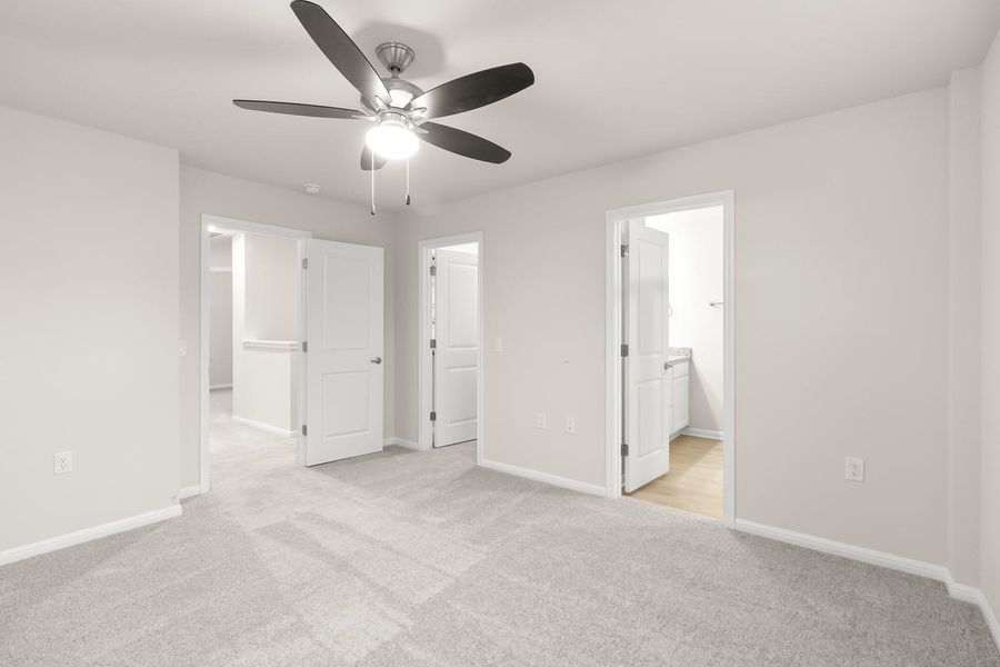 This room features light grey carpet flooring and a ceiling fan with an integrated light fixture