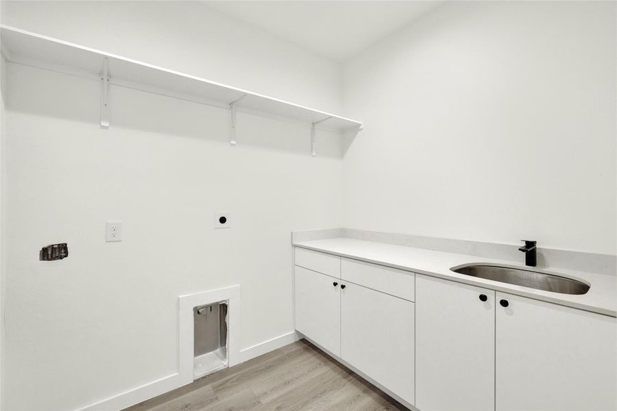 Laundry room featuring light wood-type flooring, cabinet space, and hookup for an electric dryer