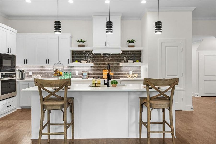 Kitchen featuring hardwood / wood-style floors, tasteful backsplash, a breakfast bar, pendant lighting, and a center island Kitchen featuring hardwood / wood-style floors, tasteful backsplash, a breakfast bar, pendant lighting, and a center island