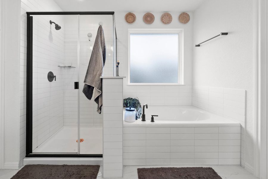 Bathroom featuring a walk-in shower with black-framed glass enclosure, built-in bathtub with black fixtures, white subway tile surround, and a privacy window
