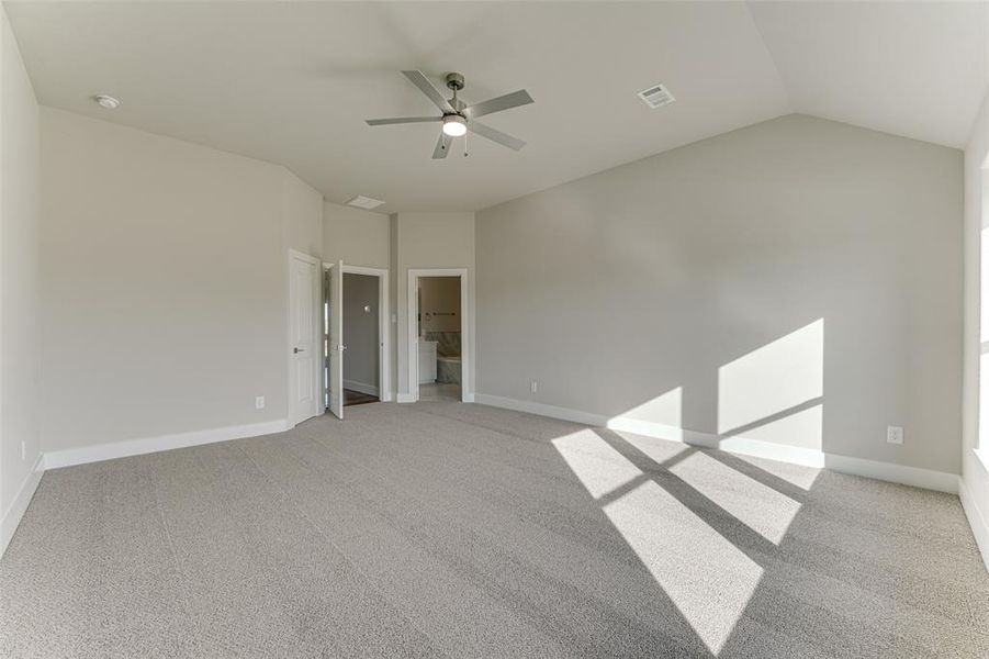 Empty room featuring ceiling fan, light carpet, and vaulted ceiling