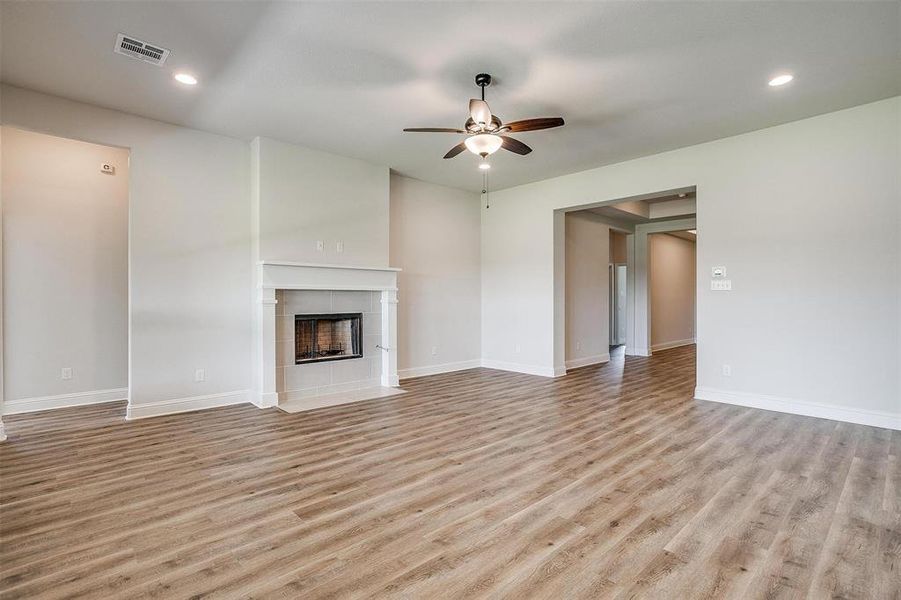 Unfurnished living room featuring a fireplace, light wood-type flooring, and ceiling fan