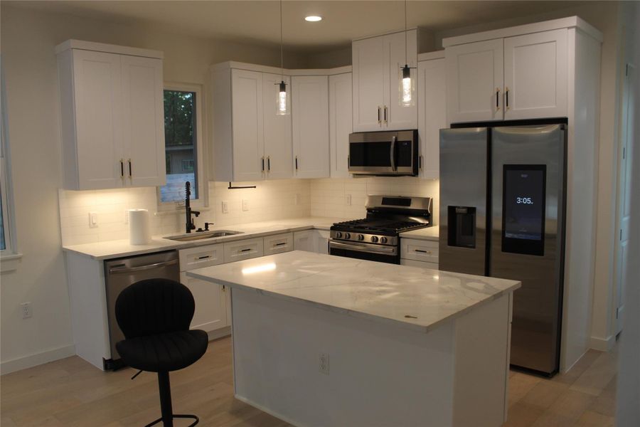 Culinary delights await in this bright kitchen, complete with an island and pristine countertops.