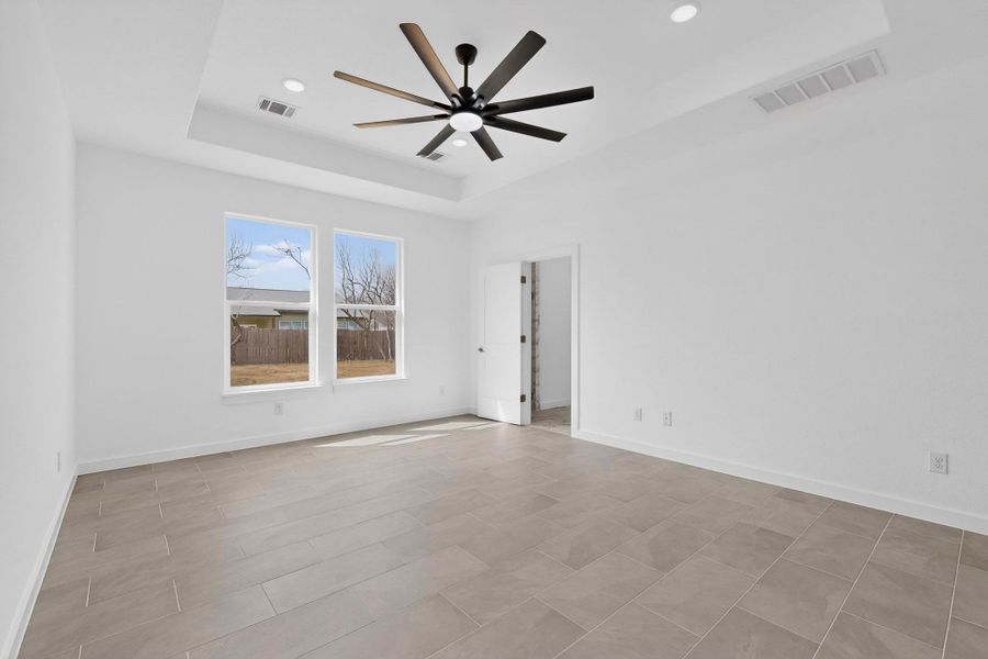 Empty room with a tray ceiling, a ceiling fan, and recessed lighting
