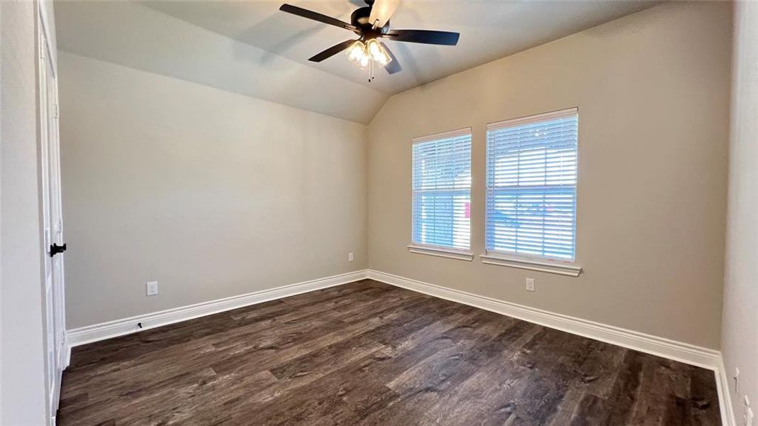 Unfurnished room featuring dark wood-type flooring, ceiling fan, and vaulted ceiling