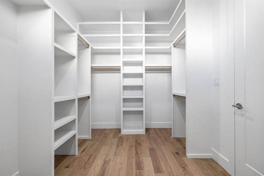 Walk in closet with light hardwood / wood-style floors