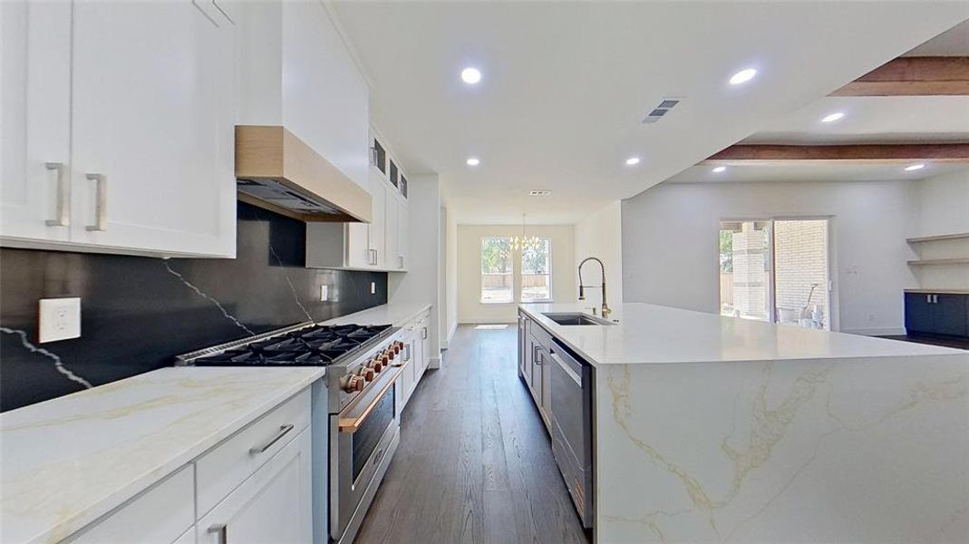 Kitchen with white cabinetry, stainless steel appliances, light stone countertops, recessed lighting, and a spacious island
