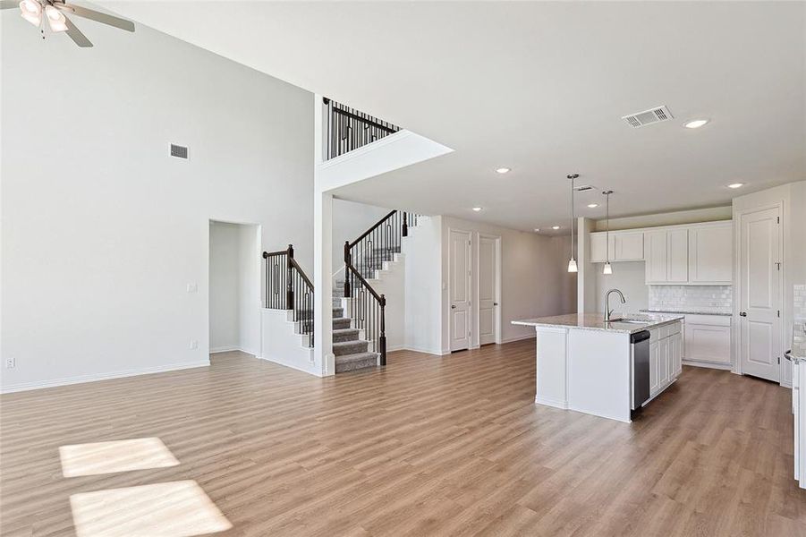 Kitchen with sink, an island with sink, dishwasher, white cabinetry, and light hardwood / wood-style floors