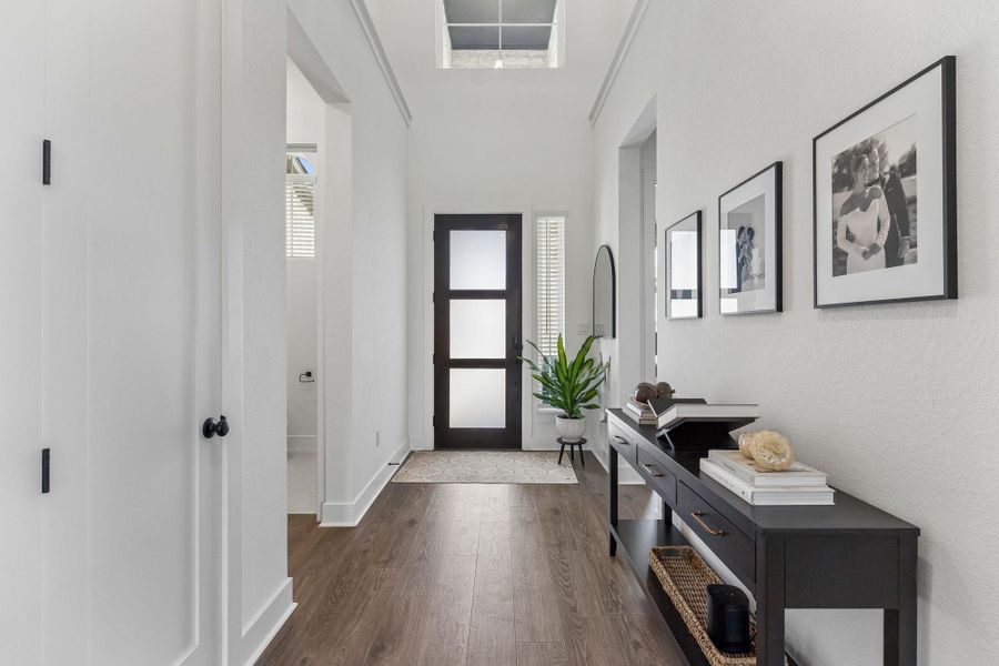 An inviting entryway welcomes guests with clean lines, rich wood floors, and soaring ceilings.