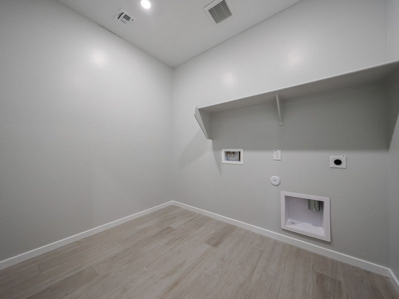 A room with a wood floor and a white wall with a vent.