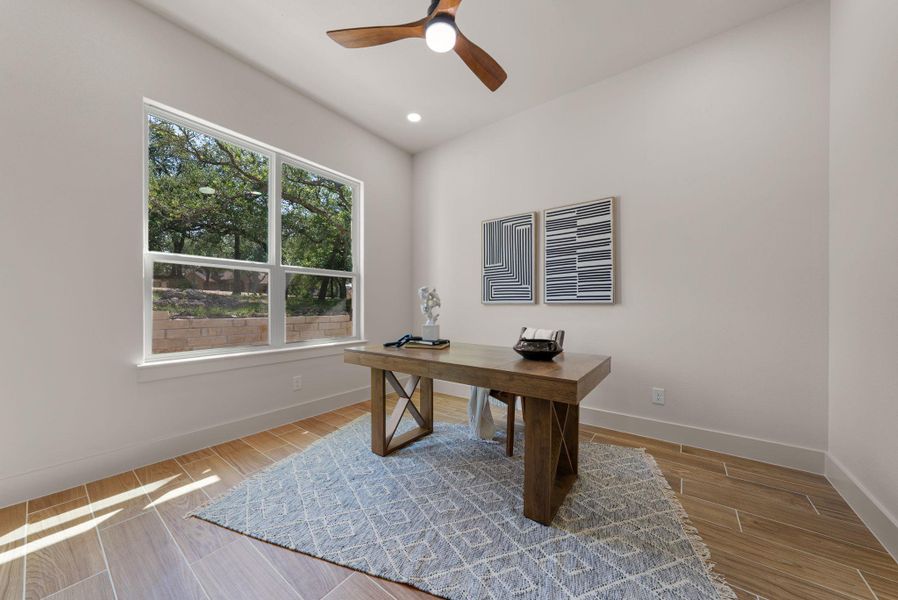A well-lit study with a large window overlooking natural surroundings provides a serene work environment.