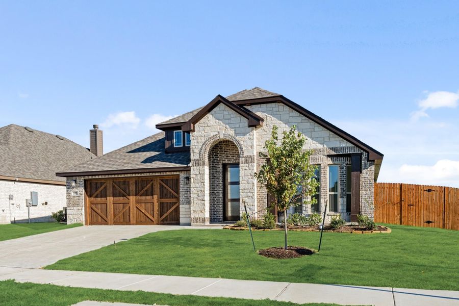 Single-story home with stone and brick exterior, arched entry, two-car wood garage doors, and manicured front lawn