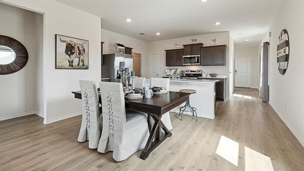 Dining area and kitchen featuring light-colored flooring, recessed lighting, and dark wood cabinetry