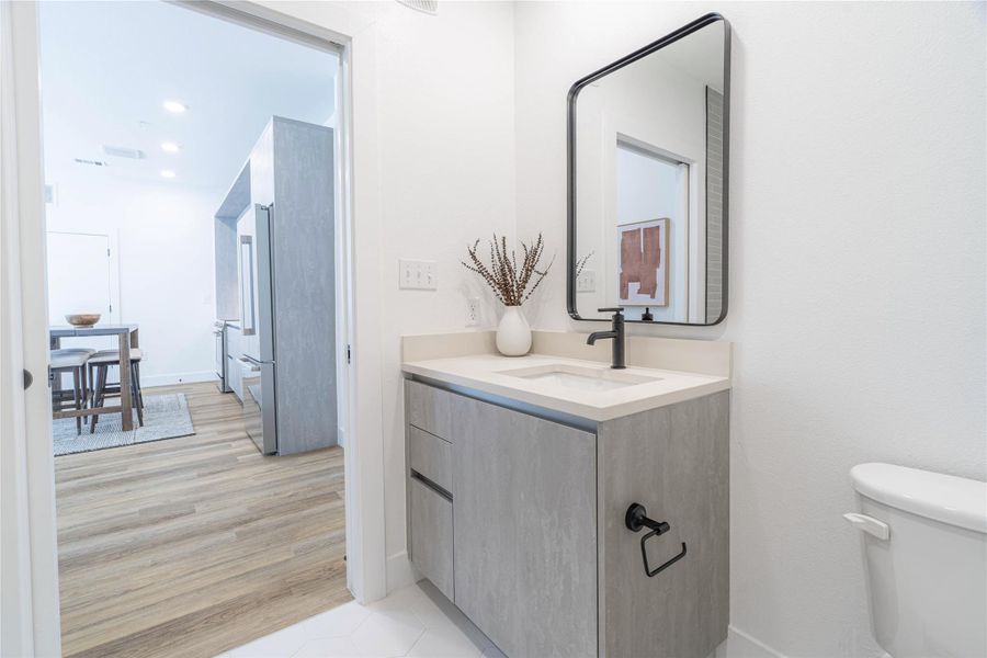 Half bath featuring vanity, recessed lighting, and light wood finished floors.Photos shown are of a model residence and are representative in nature. Actual residence may differ in layout, finishes, and views.