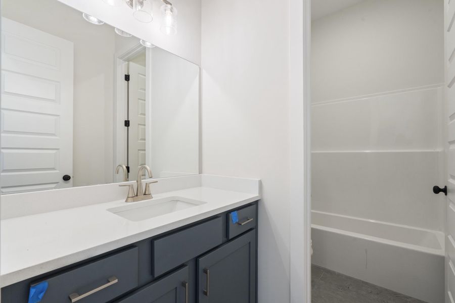 Bathroom featuring a vanity with a white countertop, undermount sink, brushed nickel faucet, and dark cabinetry