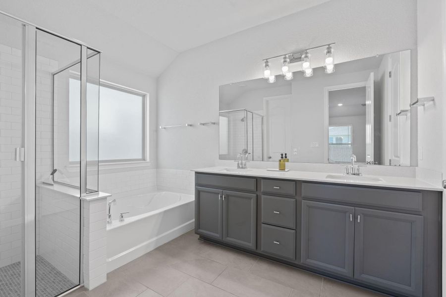 Bathroom featuring a bath, a stall shower, light tile patterned floors, and vaulted ceiling Bathroom featuring a bath, a stall shower, light tile patterned floors, and vaulted ceiling