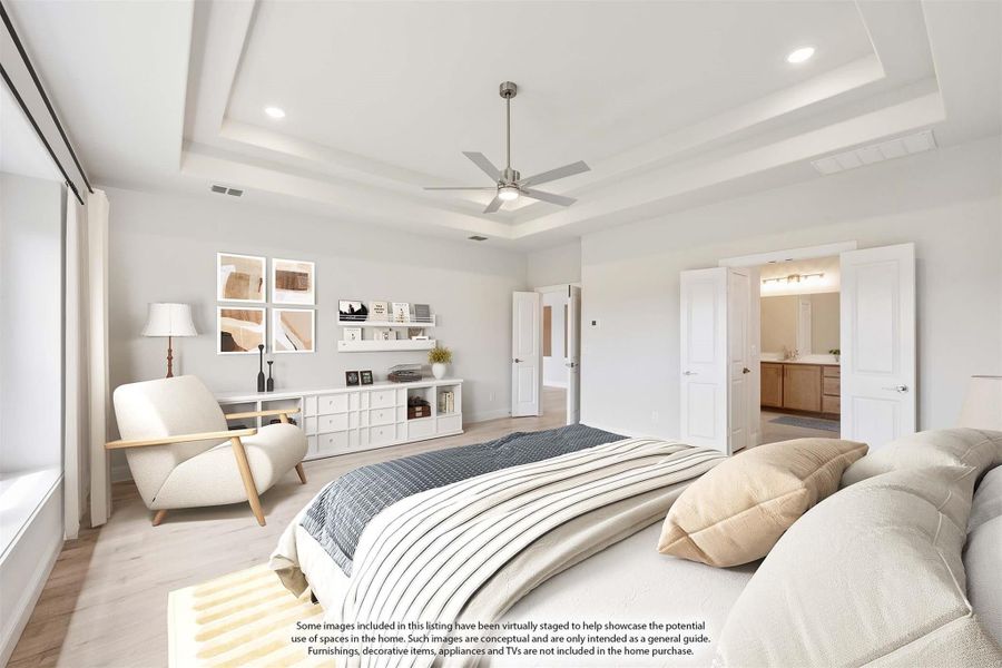 Master bedroom with tray ceiling, ceiling fan, hardwood floors, and ensuite bathroom doorway visible