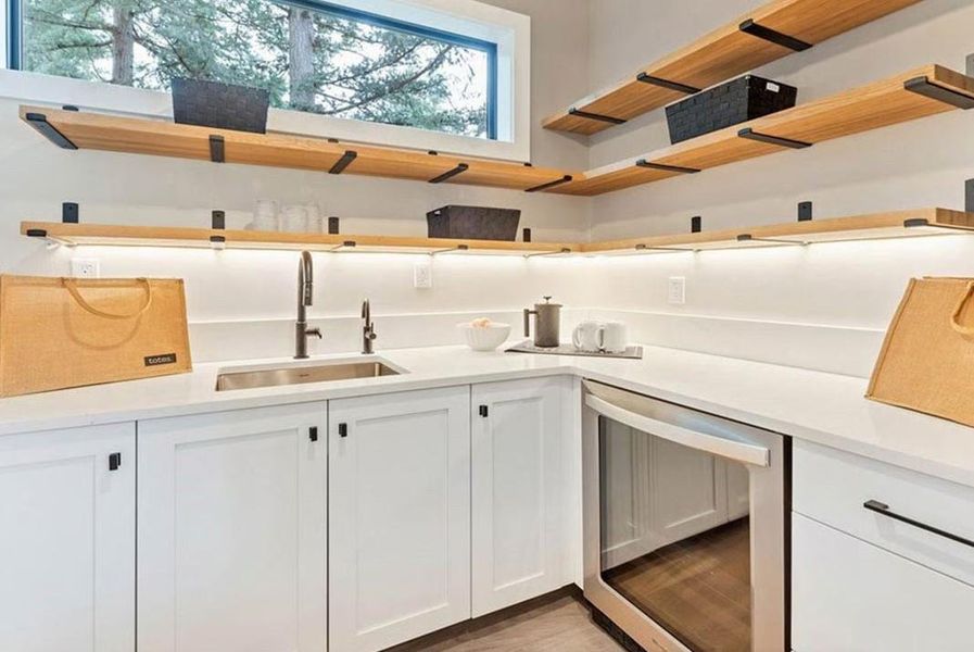 Kitchen with open shelves, white cabinets, dishwasher, and light stone countertops