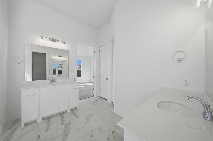 Bathroom featuring two vanities and light marble finish flooring Bathroom featuring two vanities and light marble finish flooring