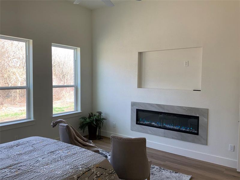 Bedroom with a high end fireplace, wood finished floors, and a ceiling fan Bedroom with a high end fireplace, wood finished floors, and a ceiling fan