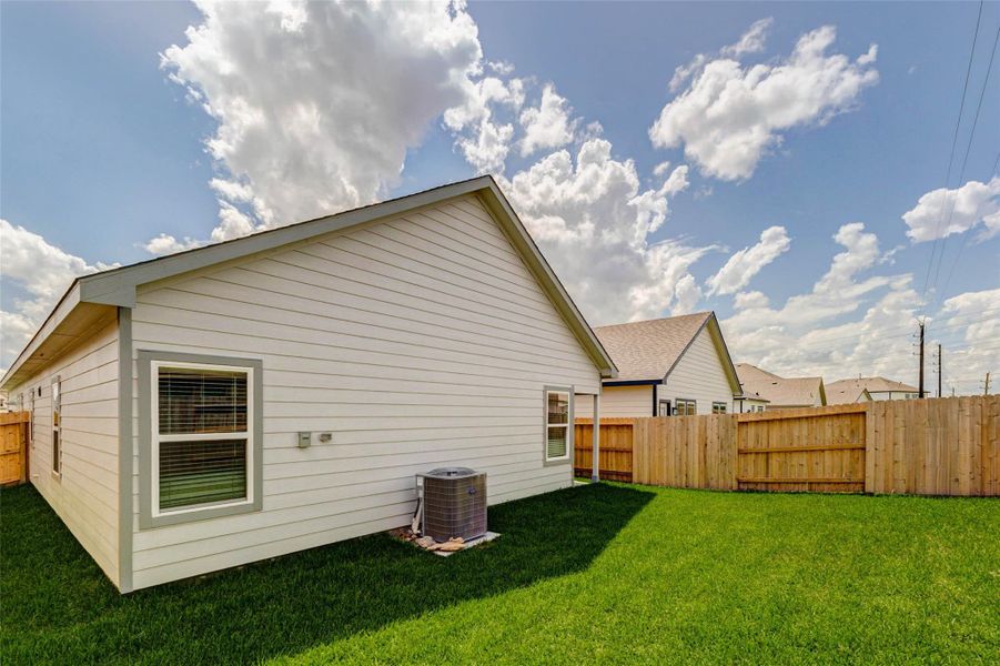Spacious backyard view with fresh grass, wood privacy fencing, side-yard access, and a clean rear exterior. The yard offers flexible outdoor space for everyday enjoyment, pets, play, or outdoor seating while remaining simple to maintain.