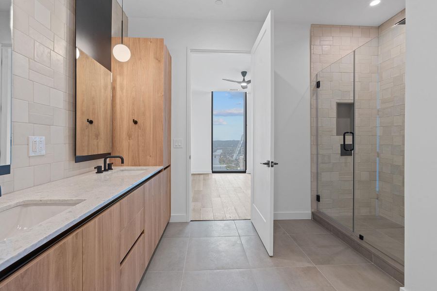 Bathroom with double vanity, a stall shower, light tile patterned floors, and decorative backsplash