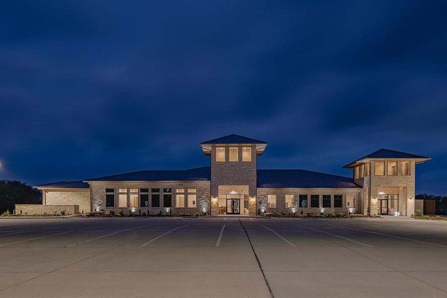Contemporary stone facade building with two prominent towers, dark metal roofing, abundant window installations, glass entry doors, and extensive paved parking Contemporary stone facade building with two prominent towers, dark metal roofing, abundant window installations, glass entry doors, and extensive paved parking