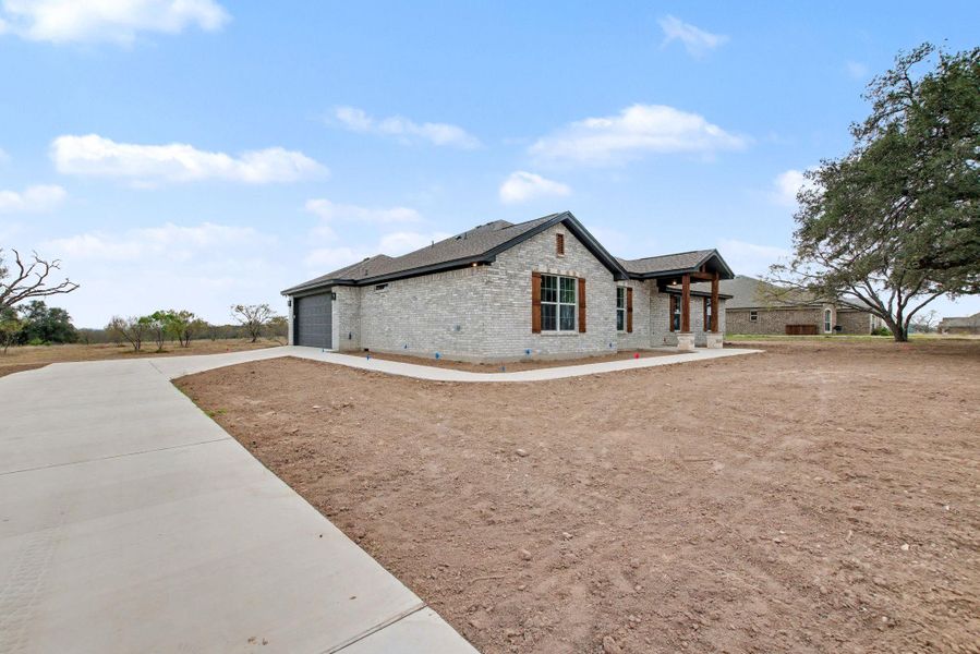 View of property exterior featuring concrete driveway, brick siding, and an attached garage