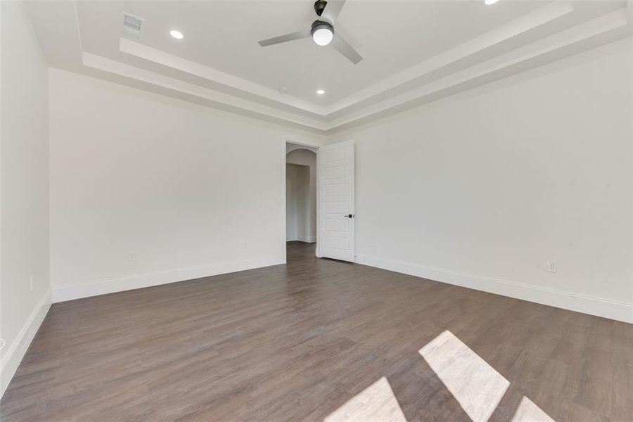 Empty room featuring ceiling fan, a tray ceiling, and dark hardwood / wood-style floors