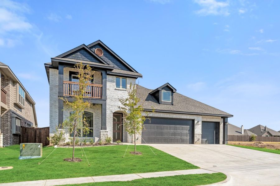 Two-story home with stone exterior, second-floor balcony, and two-car garage with concrete driveway